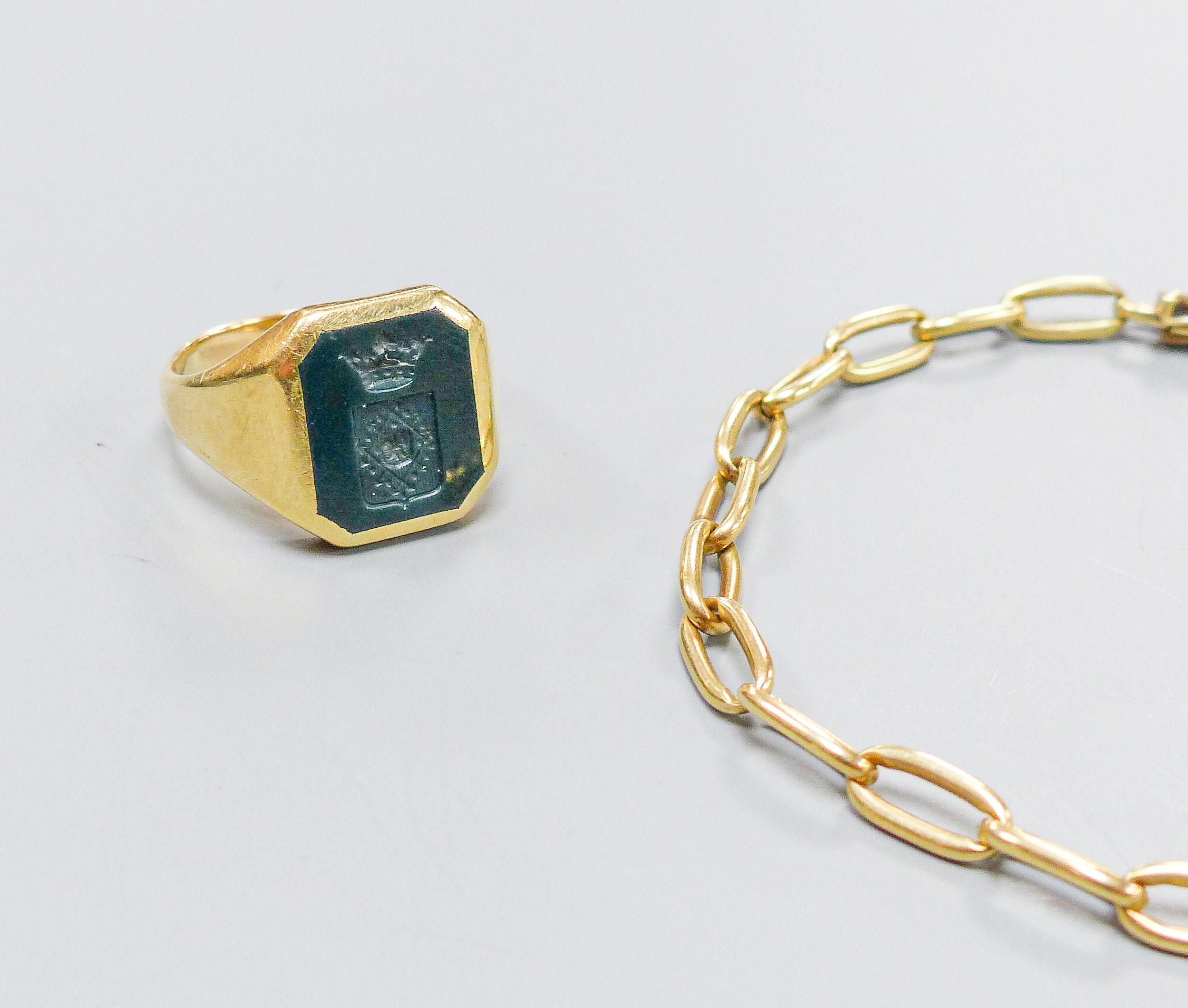 A yellow metal signet ring, inset octagonal intaglio chalcedony matrix, size U, gross 8.3 grams and a yellow metal oval-link bracelet, with box clasp, 10.5 grams.
